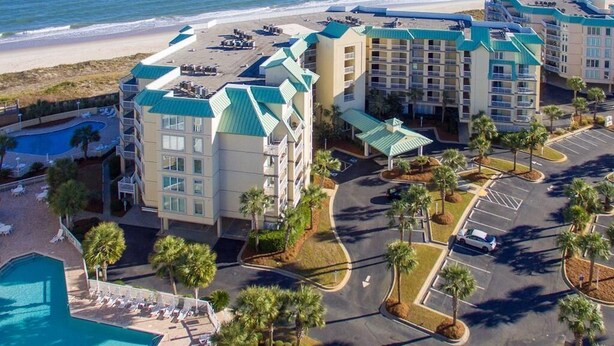 A beachfront hotel with multiple buildings, a parking lot, and a swimming pool. - Cambridge 302 Beautiful Views from Large Oceanfront Balcony (Pawleys Island)