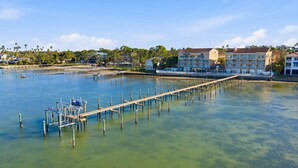 A marina with a wooden dock extending into calm waters, surrounded by residential buildings and greenery. - Waterfront Studio at Beso del Sol | Pool, Balcony, Sunset Bar (Dunedin)