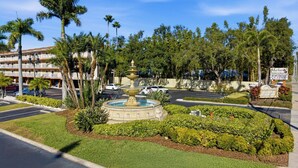 A hotel with a fountain, palm trees, and a sign indicating no dry January. - Waterfront Studio at Beso del Sol | Pool, Balcony, Sunset Bar (Dunedin)