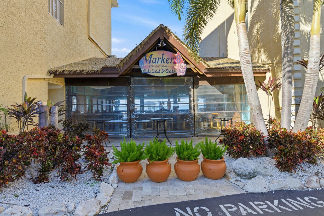 Un bar tiki llamado 'Marker8' con mesas al aire libre y plantas tropicales.