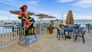 A tiki bar with outdoor seating, a statue of a pirate, and a view of the sea. - Waterfront Studio at Beso del Sol | Pool, Balcony, Sunset Bar (Dunedin)