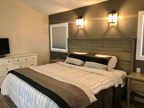 Un dormitorio con cama, cómoda, mesita de noche y dos lámparas de pared.