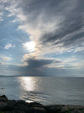 Mar tranquila con costa rocosa y cielo parcialmente nublado.