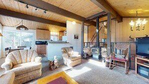 Un interior de cabaña acogedor con sala de estar, cocina y chimenea.