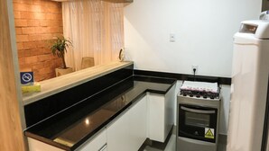 Une cuisine compacte avec un mur d’accent en briques, un plan de travail en bois et un four encastré.