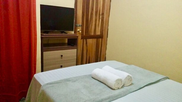 Een hotelkamer met een bed, een televisie en een houten garderobe.
