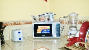 Een keuken met een magnetron, broodrooster, blender en koffiezetapparaat.
