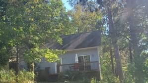 Ein Haus mit Veranda, umgeben von Bäumen und einem Rasen.