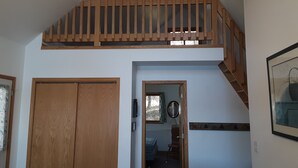 Ein Zimmer mit einer Holztreppe, einem Deckenventilator und einer Tür.