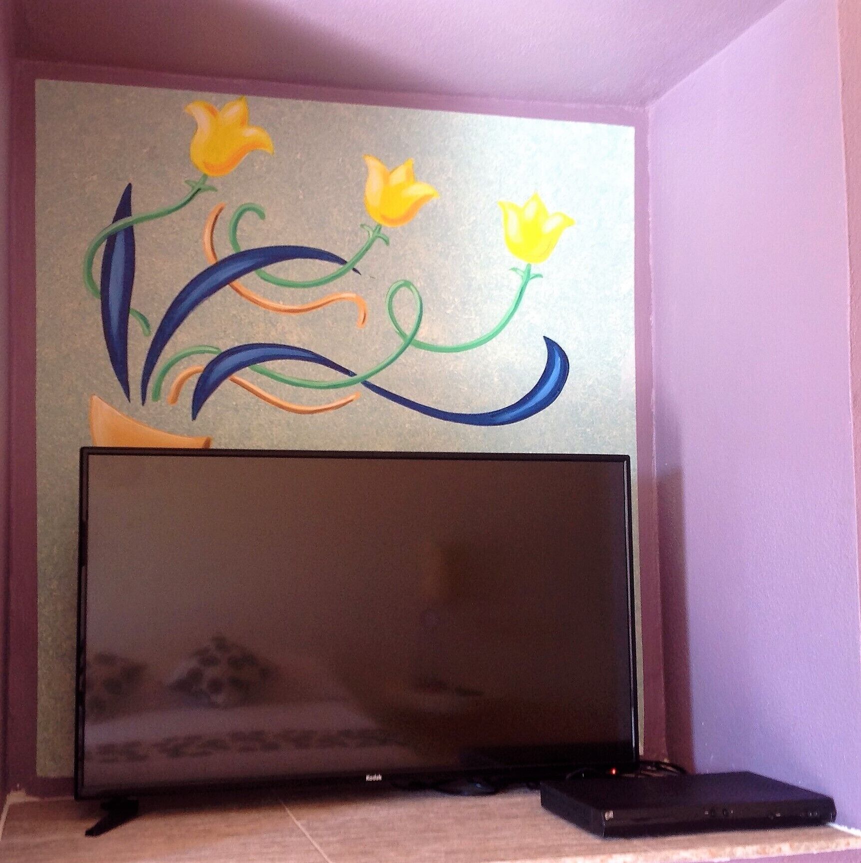Un televisor de pantalla plana montado en una pared, con un diseño floral decorativo en la parte superior.