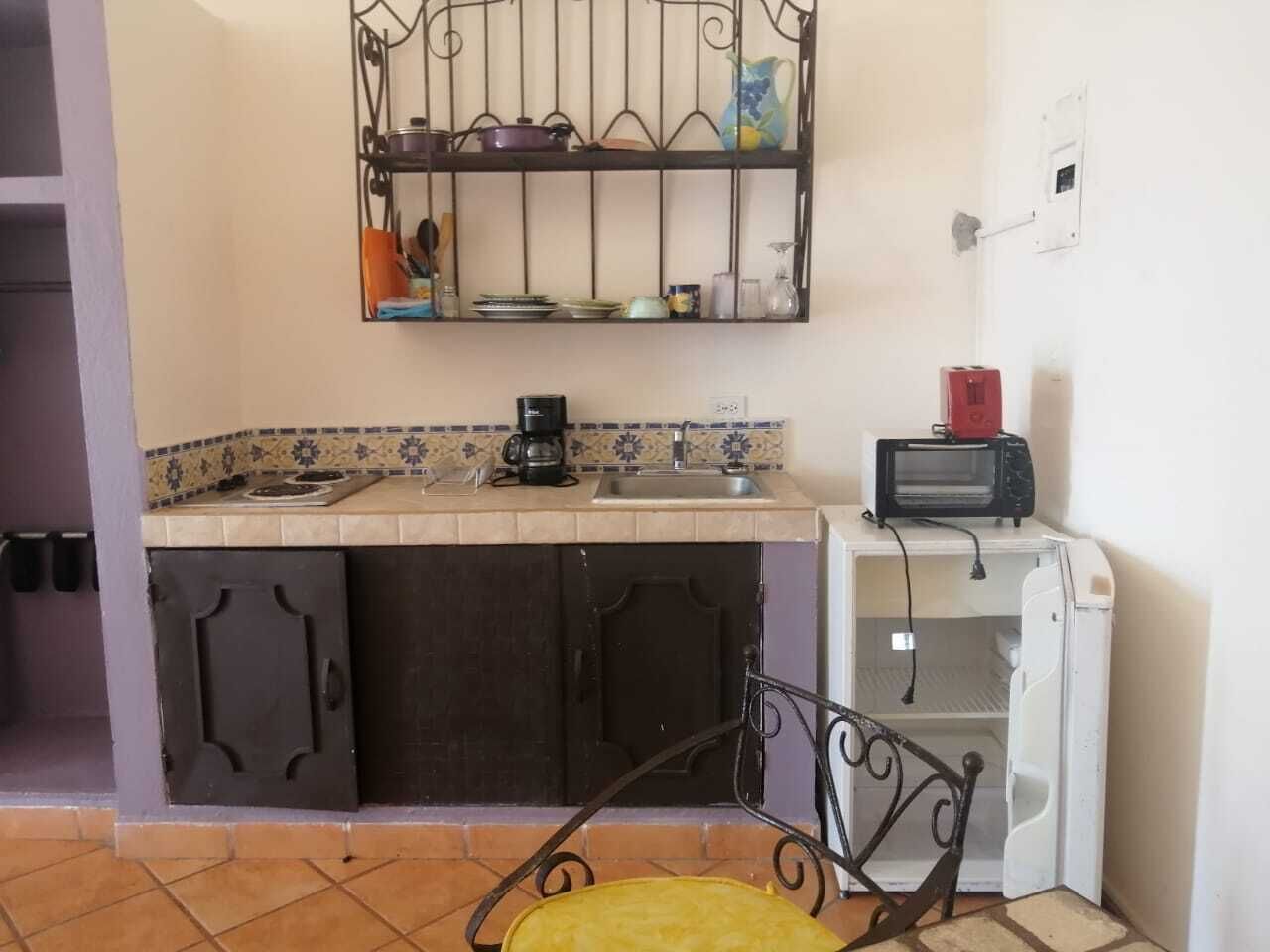 A compact kitchen with a built-in stove, a coffee maker, a microwave, and a small sink.