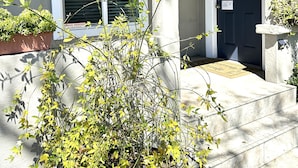 Une maison avec une porte d’entrée bleu foncé, des fenêtres à cadre blanc et un petit porche agrémenté d’un pot de fleurs.