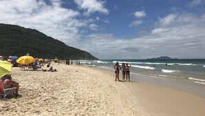 Une plage avec des parasols, des gens et des vagues.