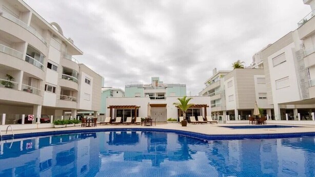 Une piscine entourée de bâtiments modernes dotés de balcons et d’espaces de détente en plein air.