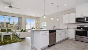 A modern kitchen with white cabinets, stainless steel appliances, and pendant lighting. - Family 4Bd Home Game Room Resort Near Disney 5147 (Kissimmee)