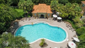 A swimming pool surrounded by lounge chairs and umbrellas, with a building in the background. - Family 4Bd Home Game Room Resort Near Disney 5147 (Kissimmee)