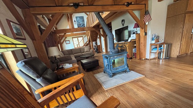 A cozy living room with a wooden ceiling, a blue wood-burning stove, leather chairs, a sofa, and a television. - Private Post & Beam Home Ideal for Family or Group Gatherings (Killington)