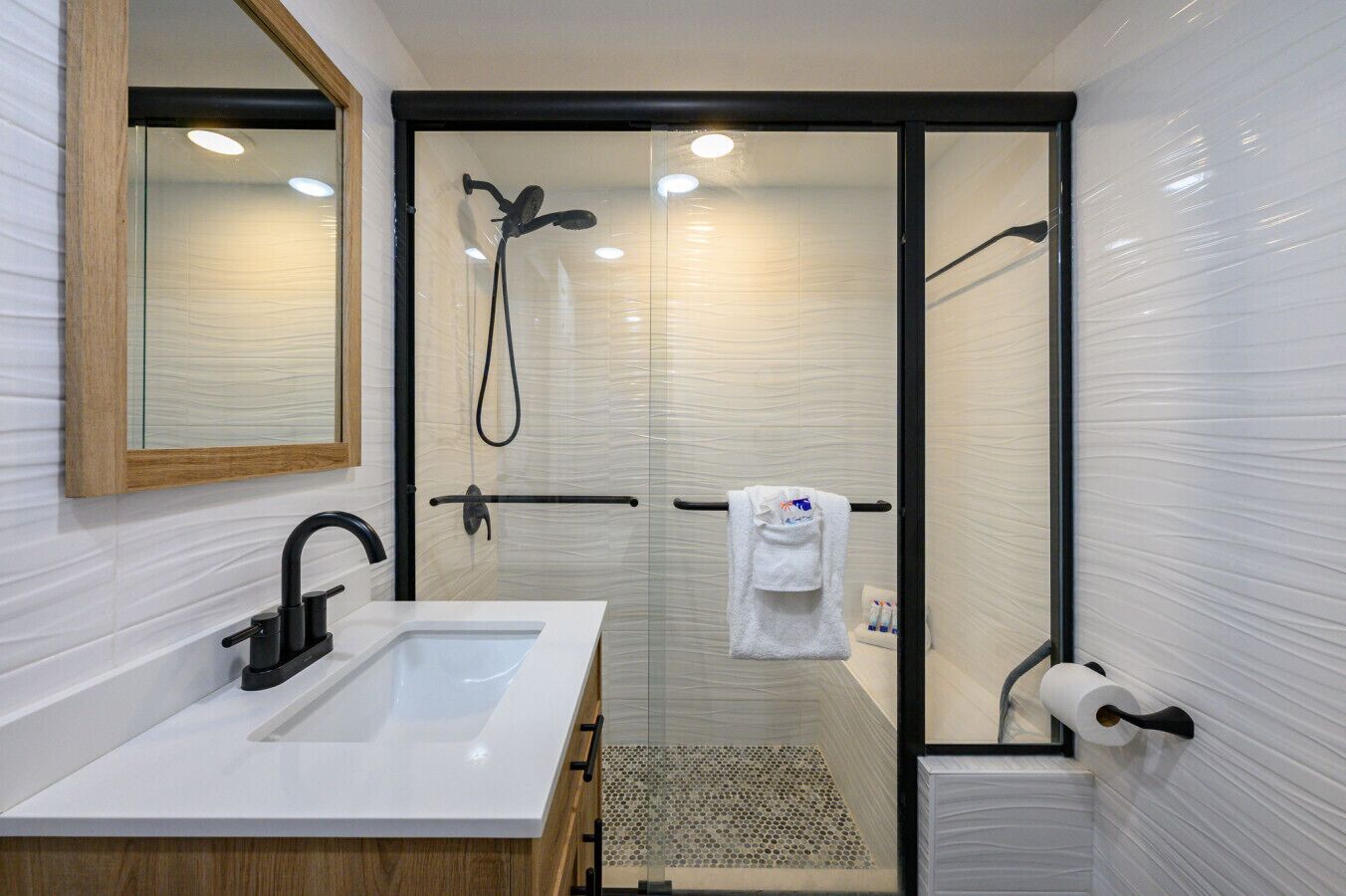 A modern bathroom with a glass-enclosed shower, a white sink, and a towel rack.