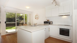 A modern kitchen with white cabinetry, a built-in oven, and a microwave. - Toorumbee 4/38 - Three Bedroom Townhouse Pet Friendly on Request* (Mooloolaba)