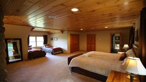 A bedroom with a large bed, a smaller bed, a wooden ceiling, and a stone wall.