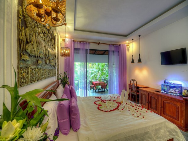 A bedroom with a bed, a television, a fish tank, and a balcony with a table and chairs. - Guests can approach the 24-hour front desk for tour arrangements, (Krong Siem Reap)