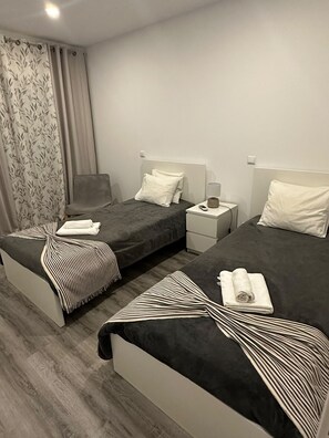 A hotel room with two beds, a chair, a nightstand, and a lamp. - REMODELED APARTMENT IN THE CITY CENTER. (FARO) (faro)