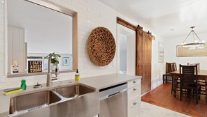 A modern kitchen with stainless steel appliances, a large mirror, and a dining area with wooden furniture.
