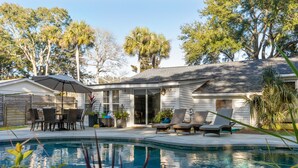 A backyard with a swimming pool, outdoor furniture, and a covered patio area.