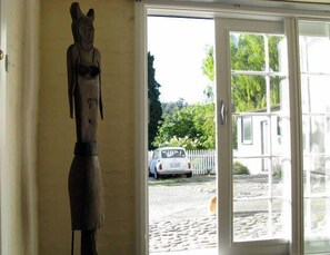 Un portale con una statua a sinistra e vista su un'auto parcheggiata e del verde circostante.