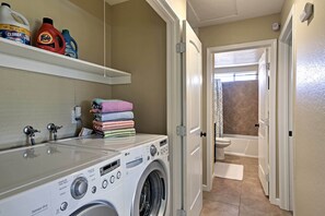 A laundry area with a washing machine, detergent bottles, and neatly stacked towels. - Private Home w/ Fire Pit & Patio by Old Town (La Quinta)