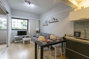 A modern living room with a dining area, a TV, and a kitchen with a sink.