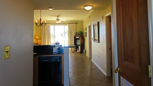 A hallway with a ceiling fan, recessed lighting, a kitchen area with a dishwasher, and a wooden door.
