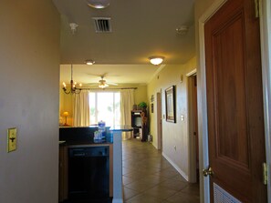 A hallway with a ceiling fan, recessed lighting, a kitchen area with a dishwasher, and a wooden door.