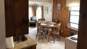Una cocina acogedora con paredes de madera, una mesa de comedor con sillas, un reloj y una ventana con cortinas.