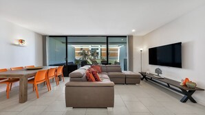 A modern living room with a sofa, dining table, chairs, and a flat-screen TV. - THE HARMONY SUITE | WIFI , Short walk to beach | Accom Holidays (TERRIGAL)