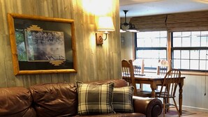 Ein gemütliches Wohnzimmer mit einem braunen Ledersofa, einem Holztisch und einem gemusterten Teppich.