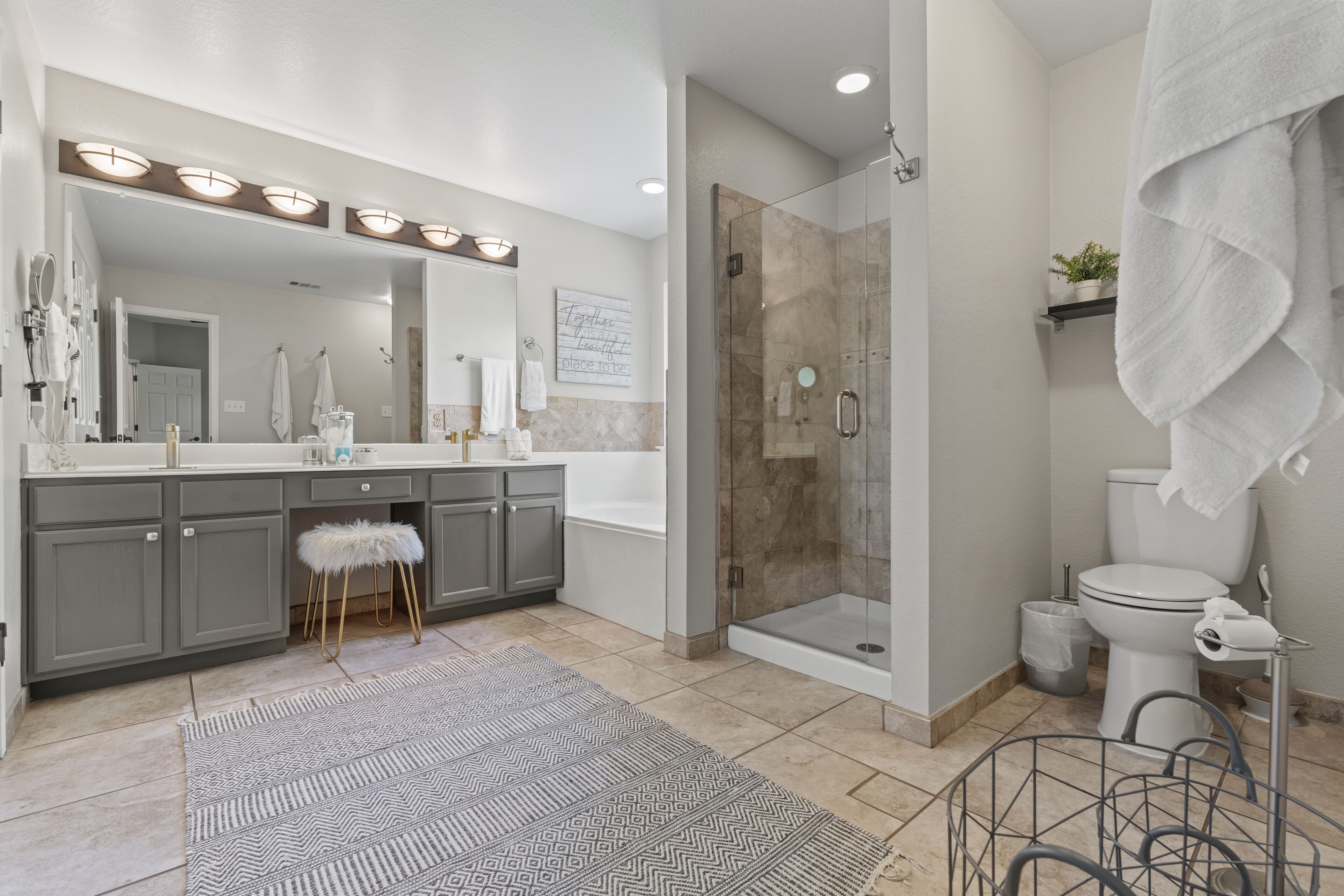 A modern bathroom with a large mirror, vanity, shower, and toilet.