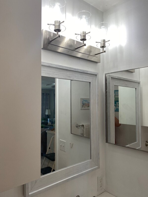 A bathroom with two large mirrors, a sink, and a light fixture above the mirrors.