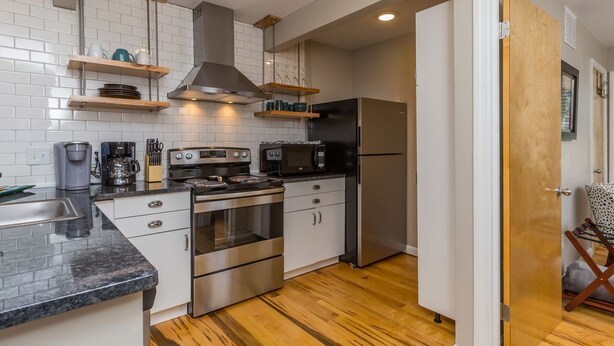 Una cocina moderna con armarios blancos, electrodomésticos de acero inoxidable y suelo de madera.