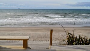 Una playa con un banco de madera y una estructura de hormigón, probablemente un paseo marítimo, que conduce a la orilla.