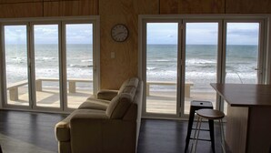 Habitación con un ventanal grande con vistas al océano, un sofá, un reloj y una zona de bar.