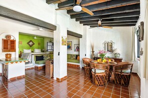 A spacious living area with a tiled floor, a dining table with chairs, a ceiling fan, and a green accent wall.