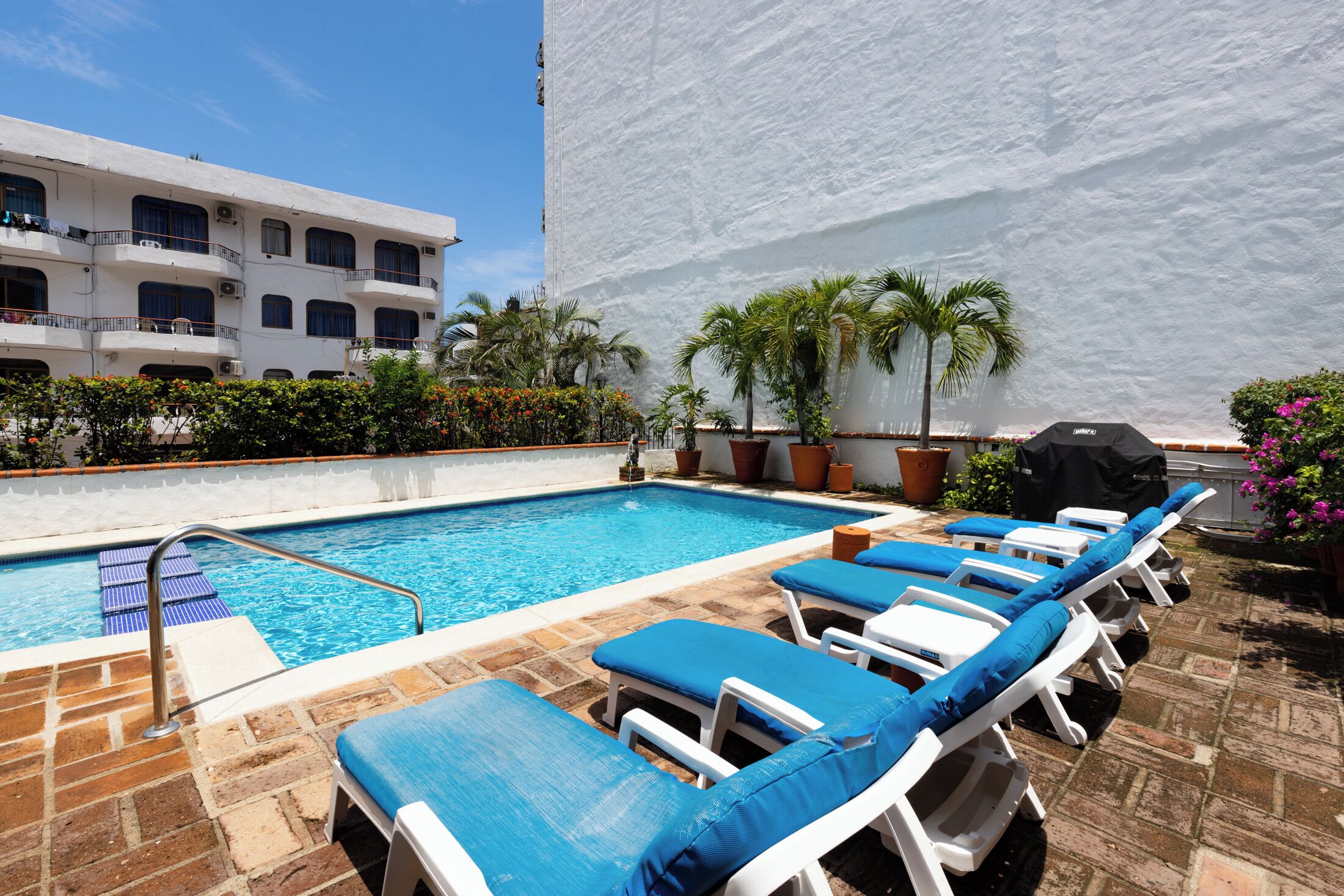 Un espace piscine avec des chaises longues et une piscine.