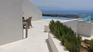 Un edificio blanco con un patio, mobiliario exterior y vistas al mar.