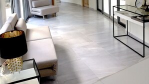 Ein geräumiges Wohnzimmer mit einer Couch, einem Glastisch und einem modernen Deckenventilator.