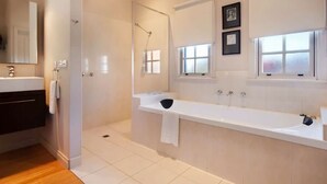 Un baño moderno con una bañera grande, zona de ducha separada y tocador con espejo.