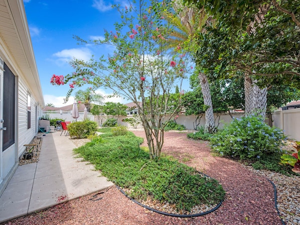 A residential backyard with a garden, a patio, and a house.