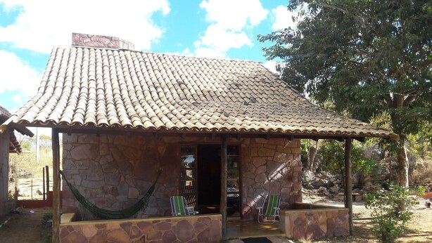 A stone building with a tiled roof, a hammock, and a small porch area.