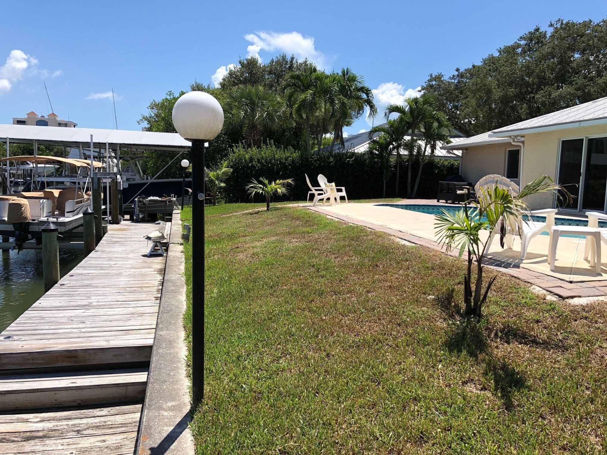 A marina with boats docked, a grassy area with a pool, and outdoor furniture.