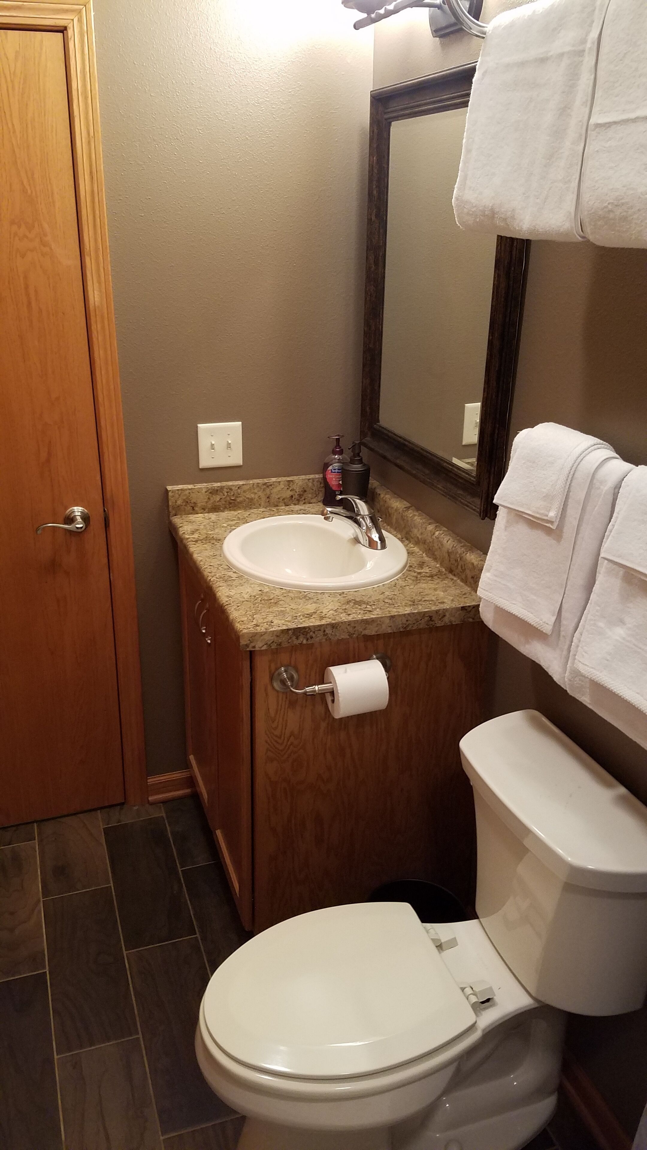 Une salle de bain avec un lavabo blanc, un miroir, des toilettes et une serviette accrochée au mur.